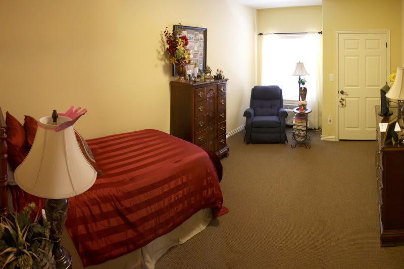 A cozy bedroom with a single bed, armchair, and traditional furniture.