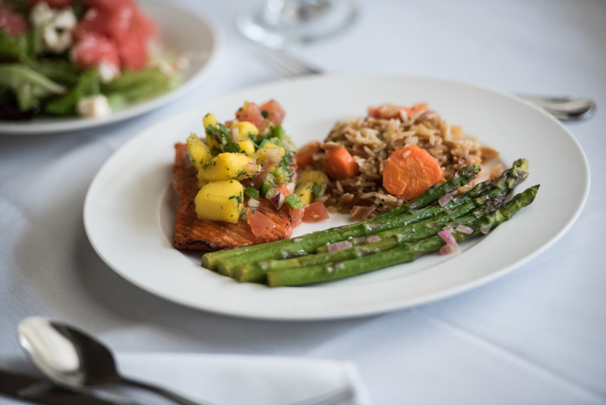 A gourmet dinner plate featuring asparagus, a vegetable medley, and seasoned grains.