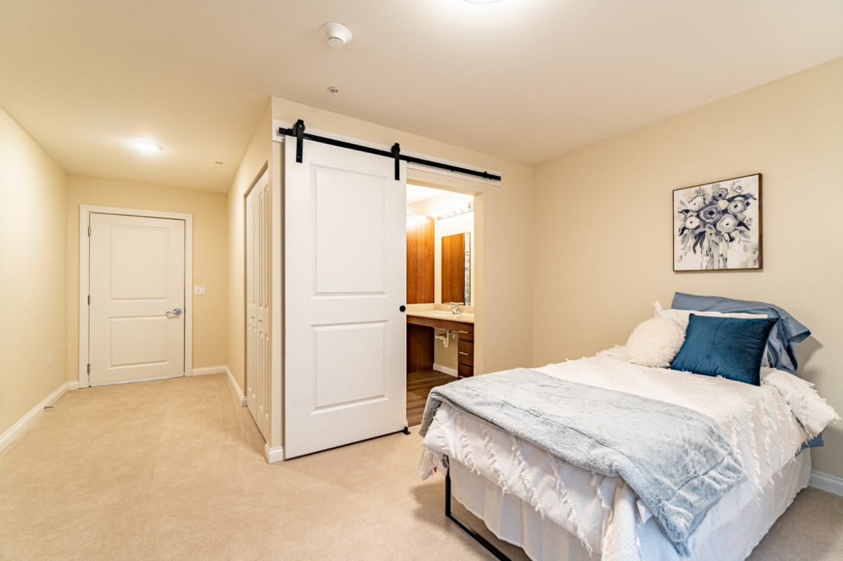 A cozy bedroom featuring a bed with blue accents, sliding closet doors, and soft lighting.