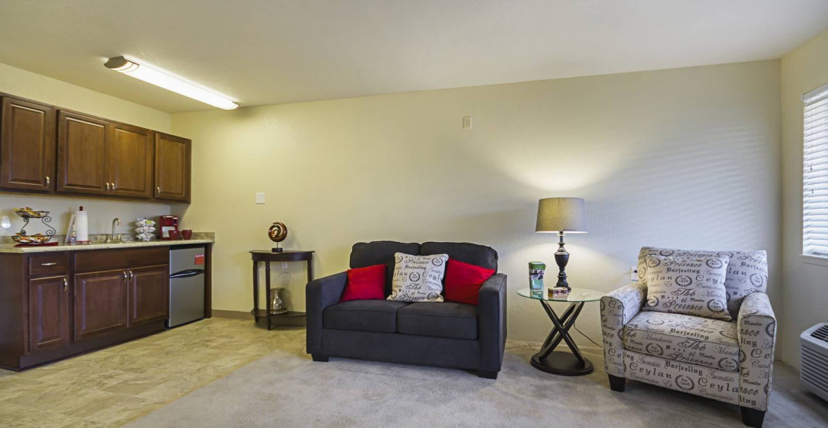 A cozy living room with a small sofa, side tables, and a lamp.