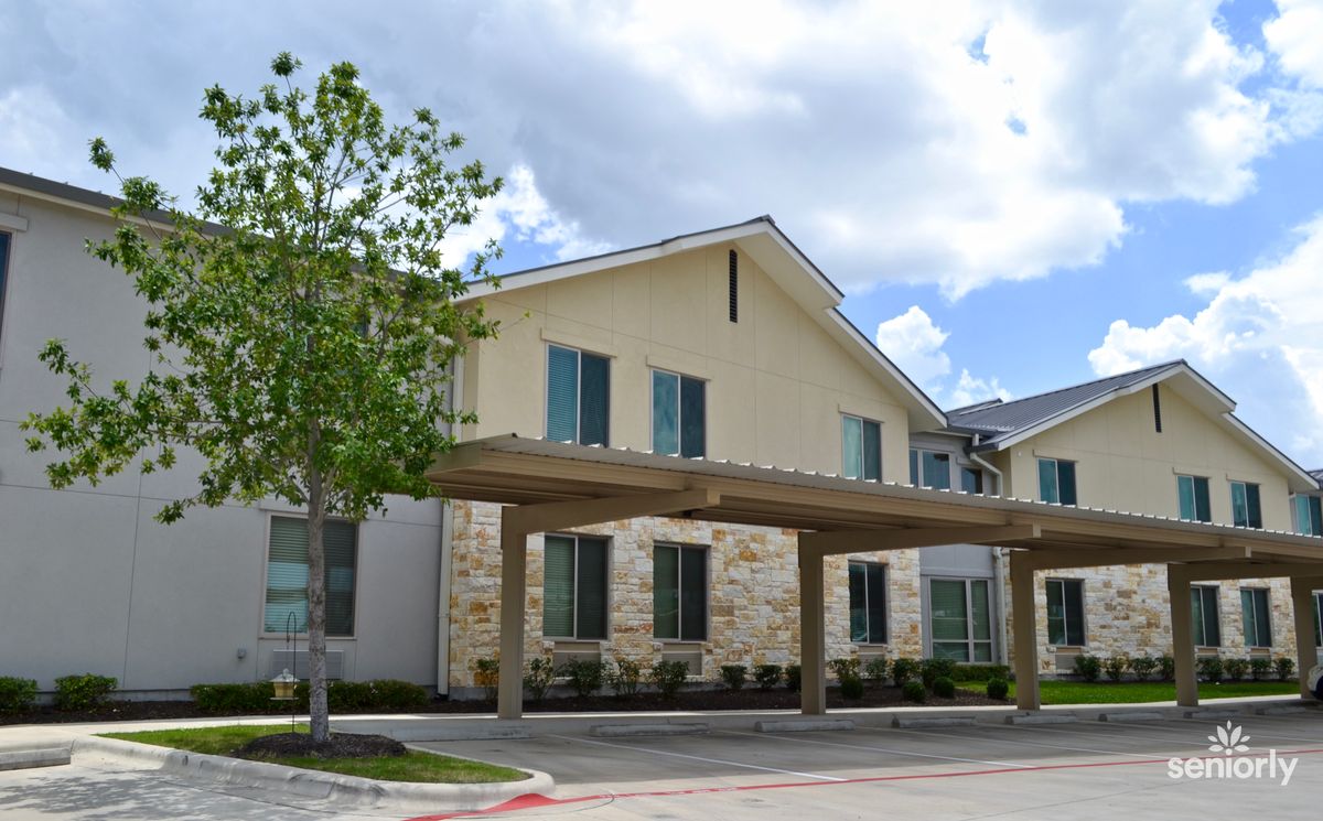 A modern residential building with stone and beige exterior under a cloudy sky.