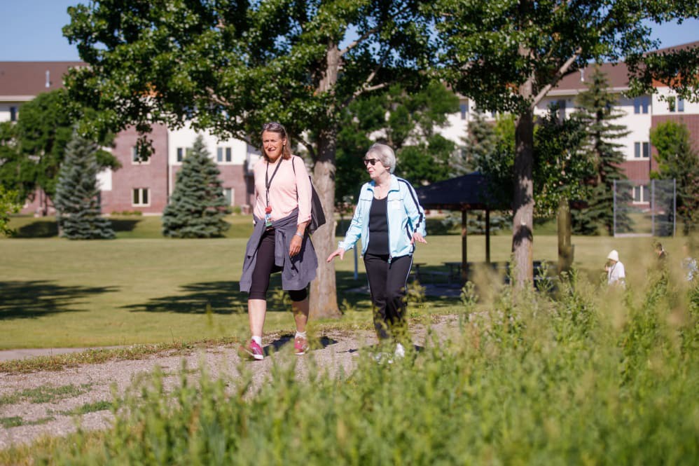Two people enjoying a walk in the park on a sunny day.