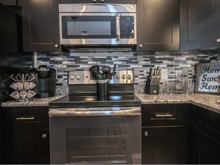 A modern kitchen setup featuring a microwave and oven with a stylish backsplash.