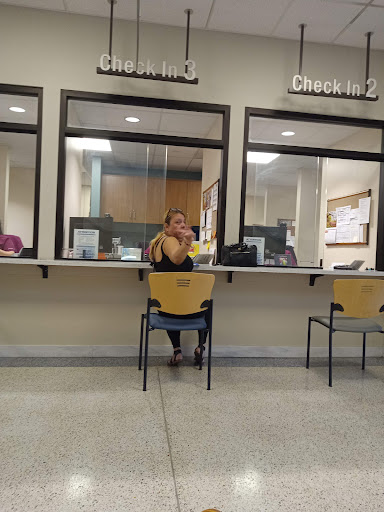 A woman sitting in a waiting area, likely at a customer service office.