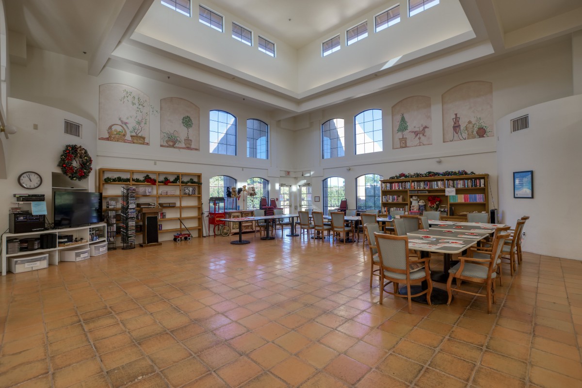 A spacious library interior featuring large windows, bookshelves, and a comfortable reading area.