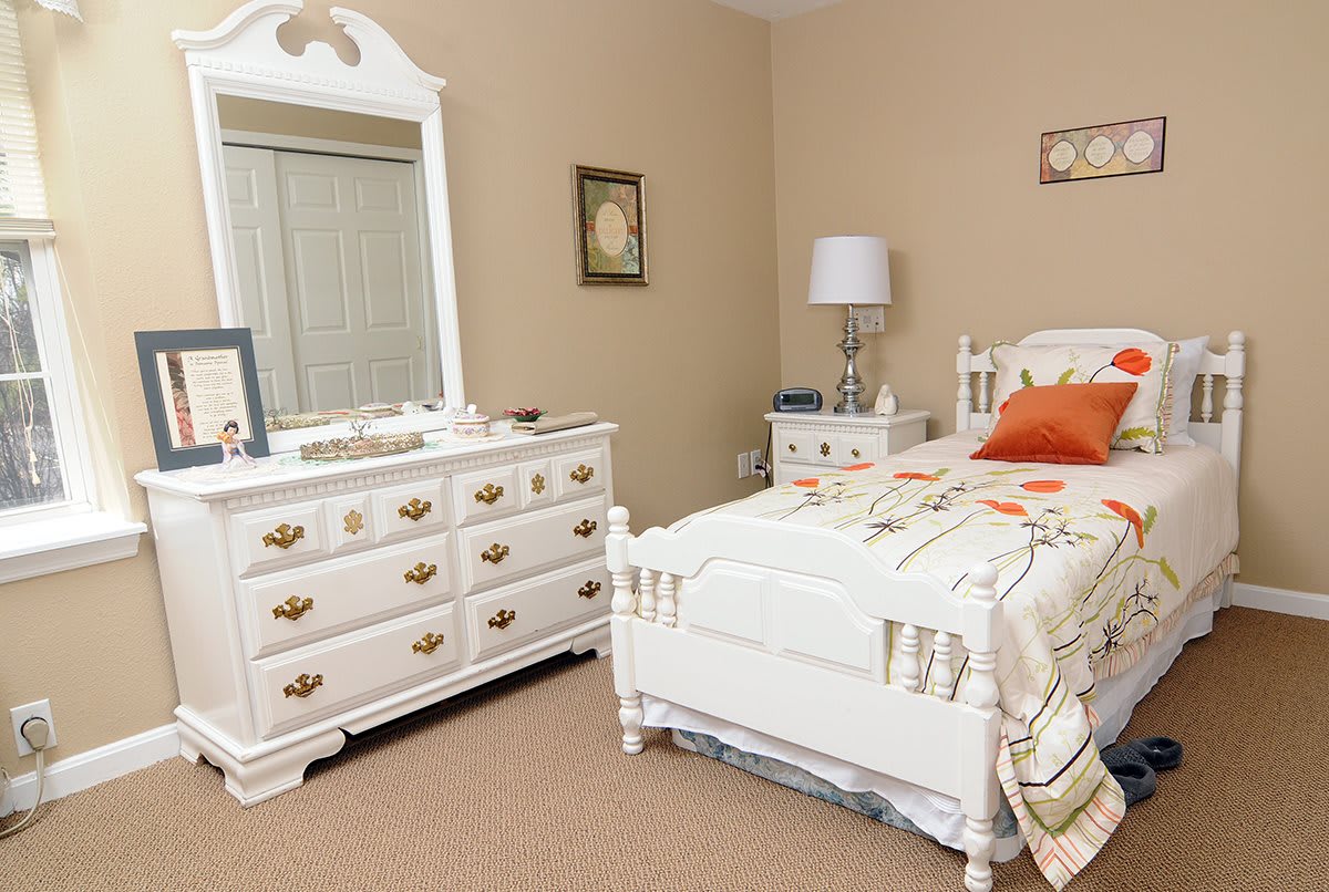 A cozy bedroom featuring a white bed and dresser with matching decor.