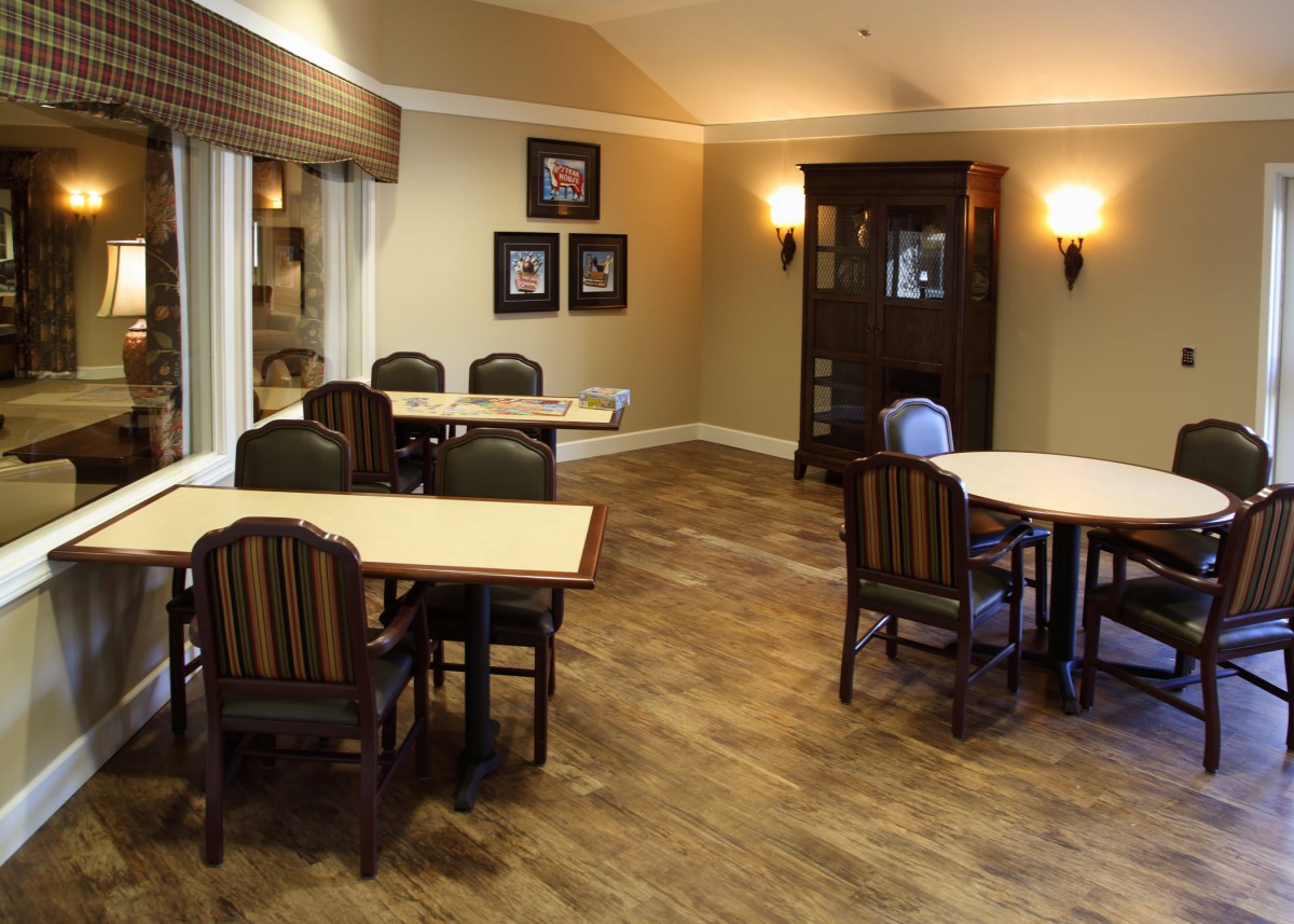 A cozy dining area with wooden tables and chairs, set in a warmly decorated interior.