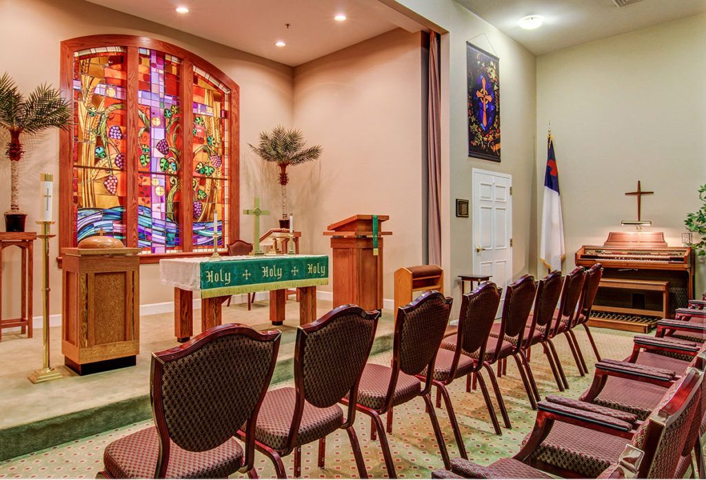 Interior of a church chapel featuring stained glass windows and seating arrangements.