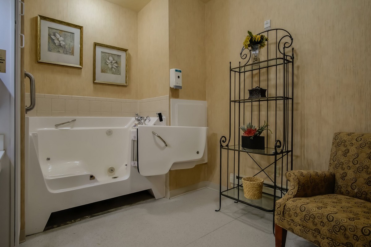 A cozy bathroom with a walk-in bathtub, decorative shelf, and wall art.