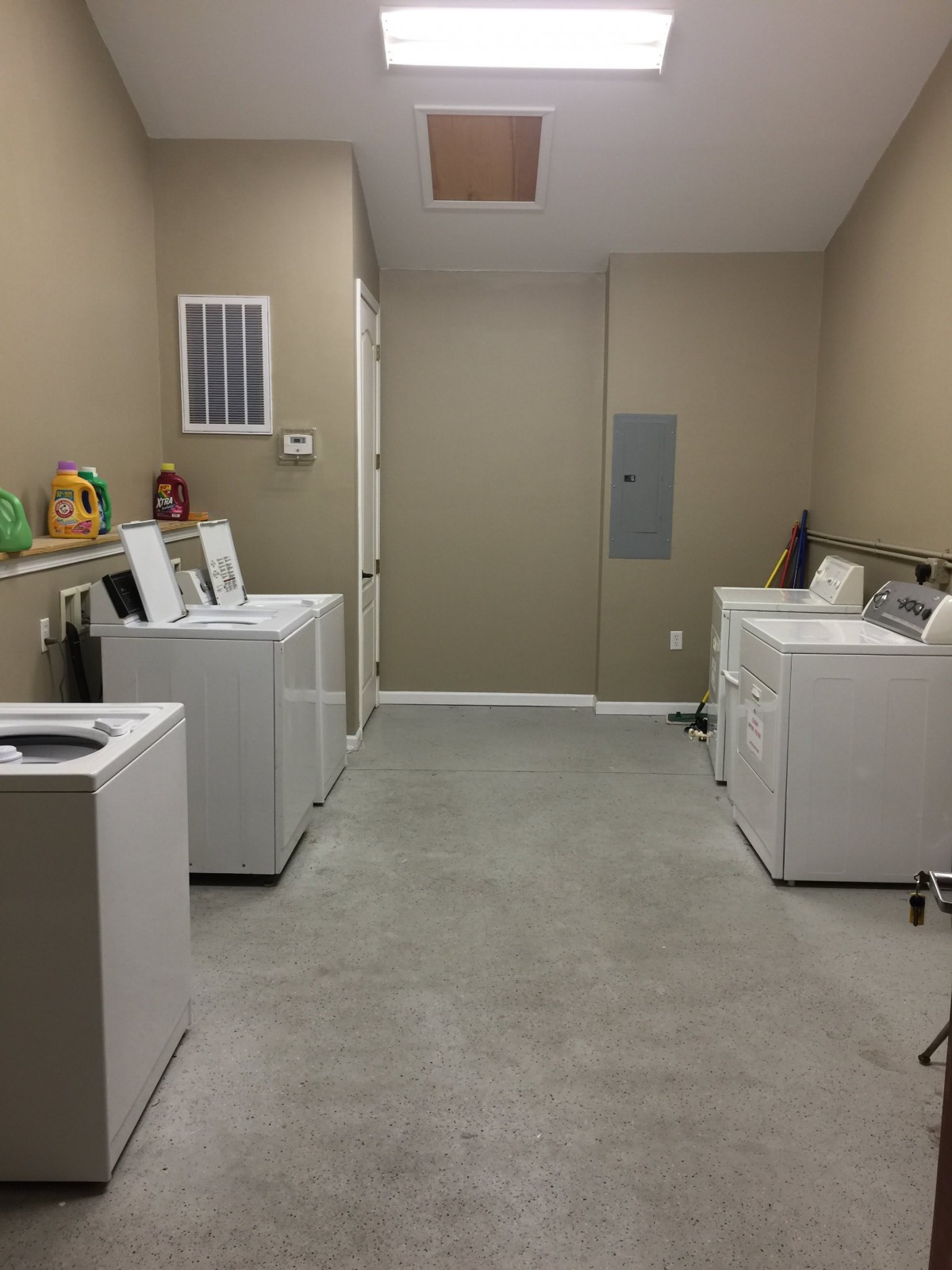 A spacious laundry room featuring multiple washing machines and dryers.