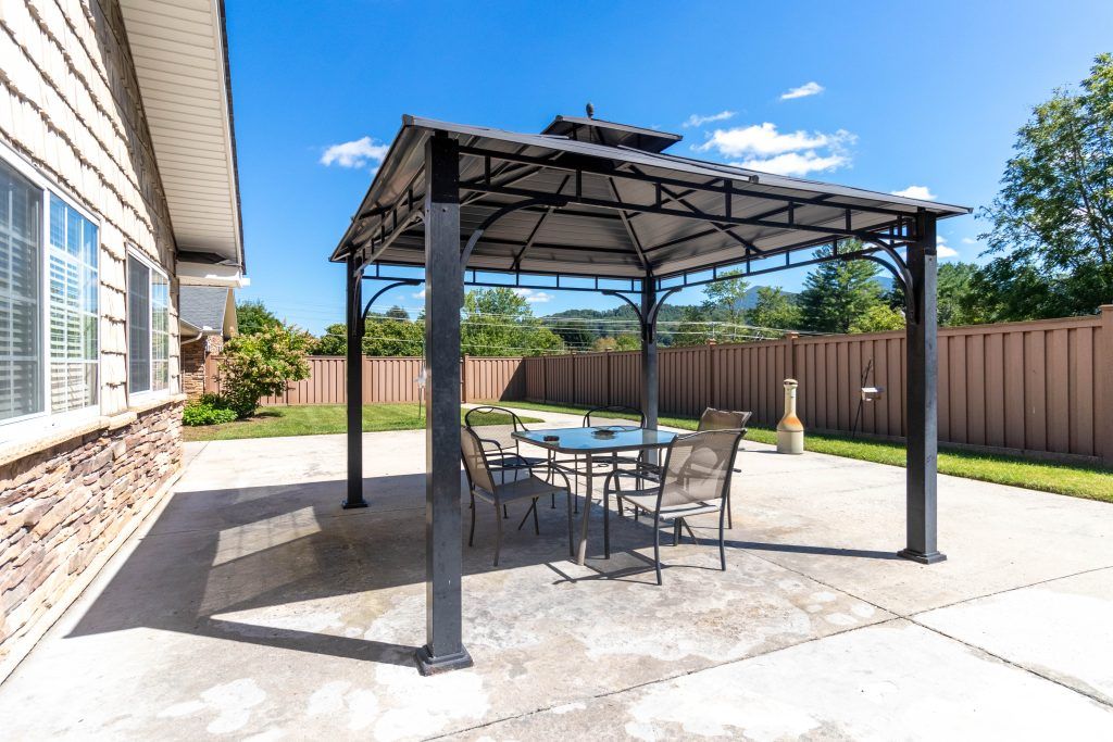 A sunny backyard patio with a gazebo and outdoor furniture.