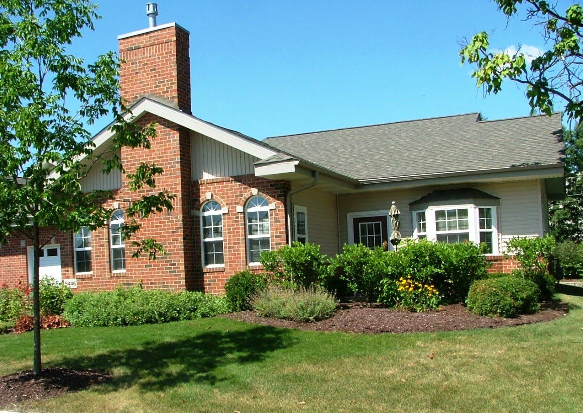 A brick house with well-maintained landscaping and a green lawn.