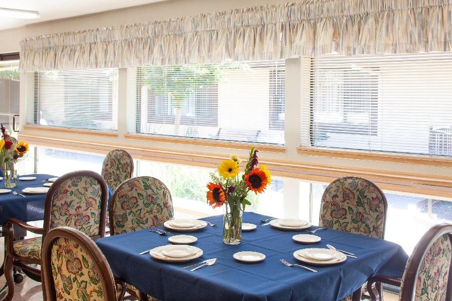 A dining table set with plates and a vase of sunflowers, bathed in natural light.