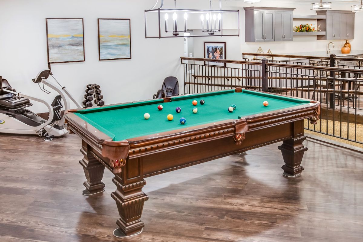 A stylish game room featuring a classic wooden pool table on a polished wooden floor.
