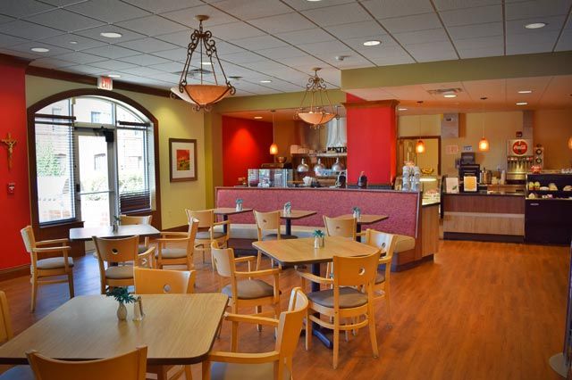A cozy cafe interior with wooden tables and chairs, warm lighting, and inviting decor.