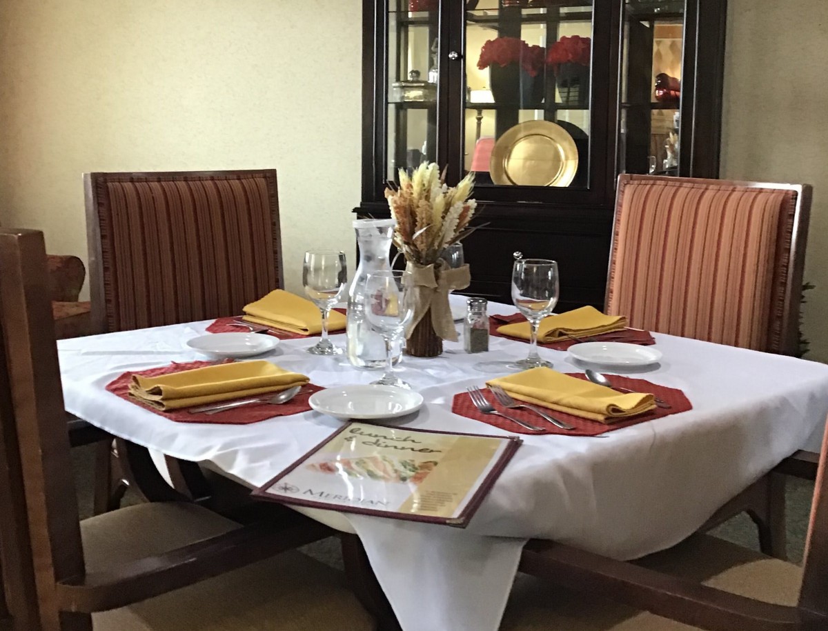 A beautifully set dining table in a restaurant, complete with napkins, glasses, and cutlery.