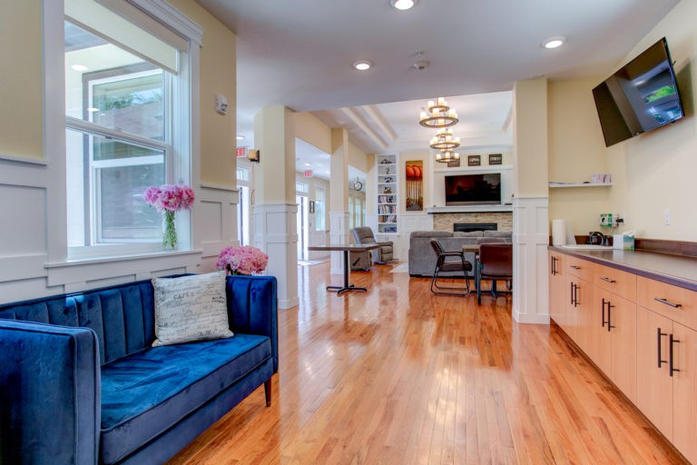 A modern, open-concept living area with hardwood floors, decorated with a blue sofa and floral accents.