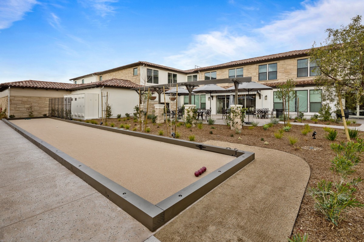 Modern residential building with a landscaped backyard featuring a bocce court.