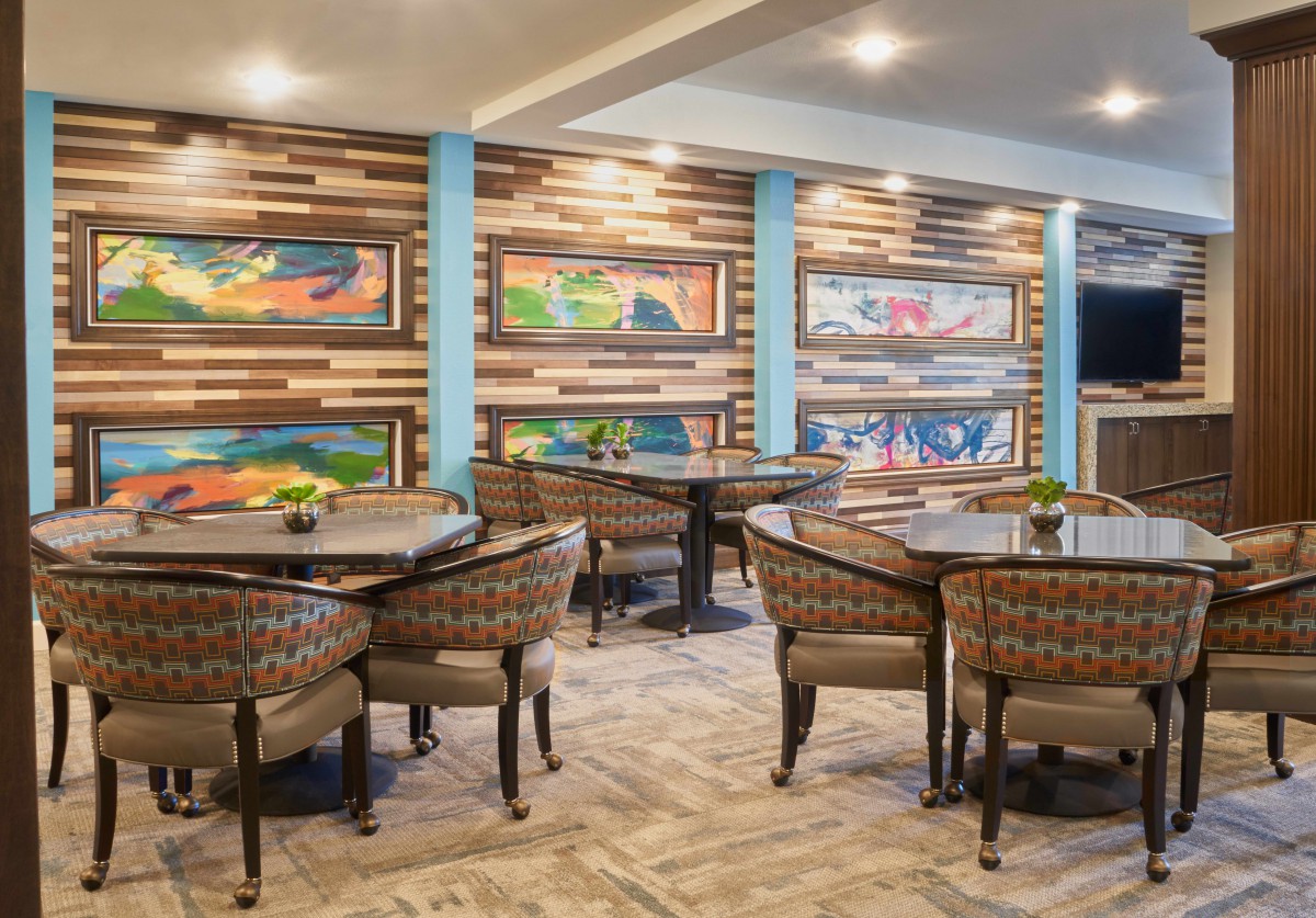 A well-decorated restaurant interior featuring colorful wall art, neatly arranged tables and chairs, and ambient lighting.