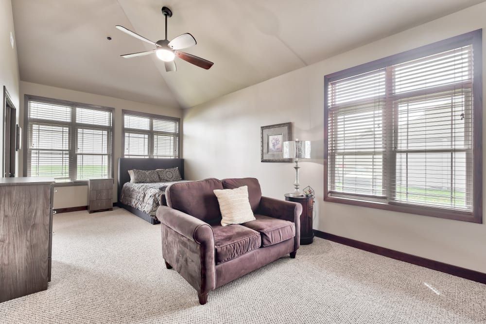 A spacious bedroom with a cozy sofa, bed, and large windows.