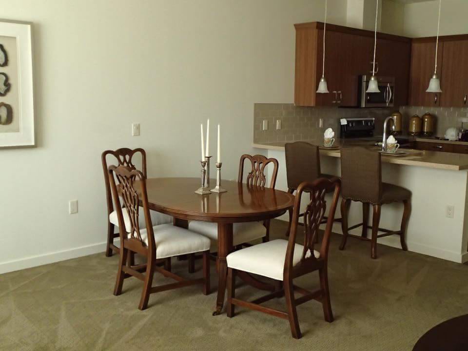 A dining area with a wooden table and chairs, adjacent to a kitchen with bar seating.