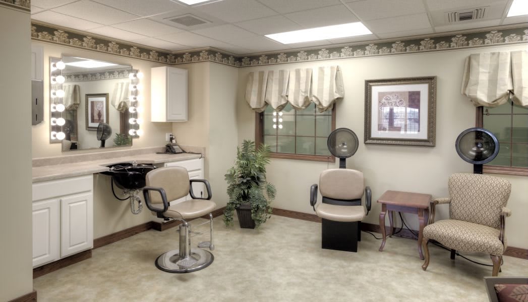 A cozy hair salon interior with chairs and a mirror.