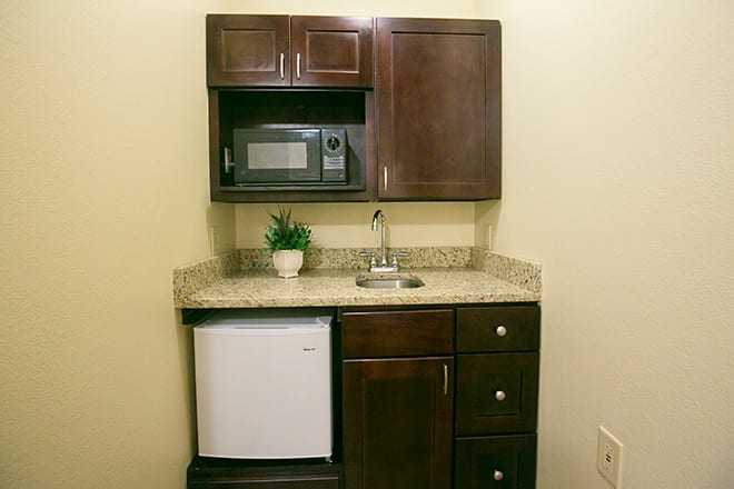 A compact kitchenette with a microwave, mini fridge, and granite countertop.