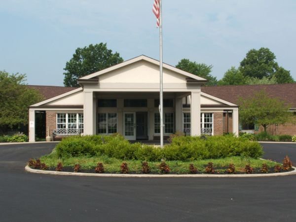 A building entrance with an American flag and surrounding greenery.