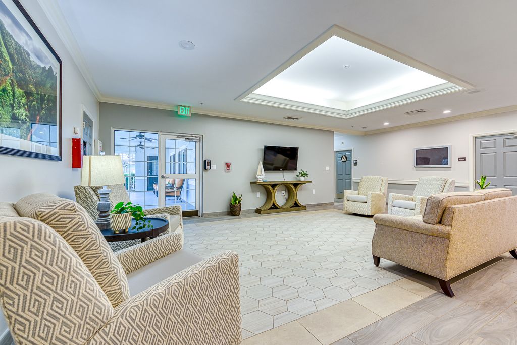 A bright and modern lobby featuring comfortable seating, a television, and decorative plants.