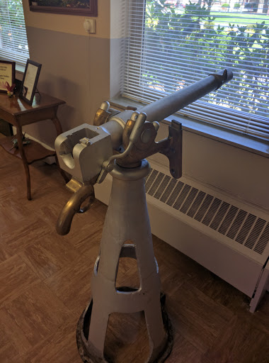 A vintage telescope positioned by a window, surrounded by wooden furniture.