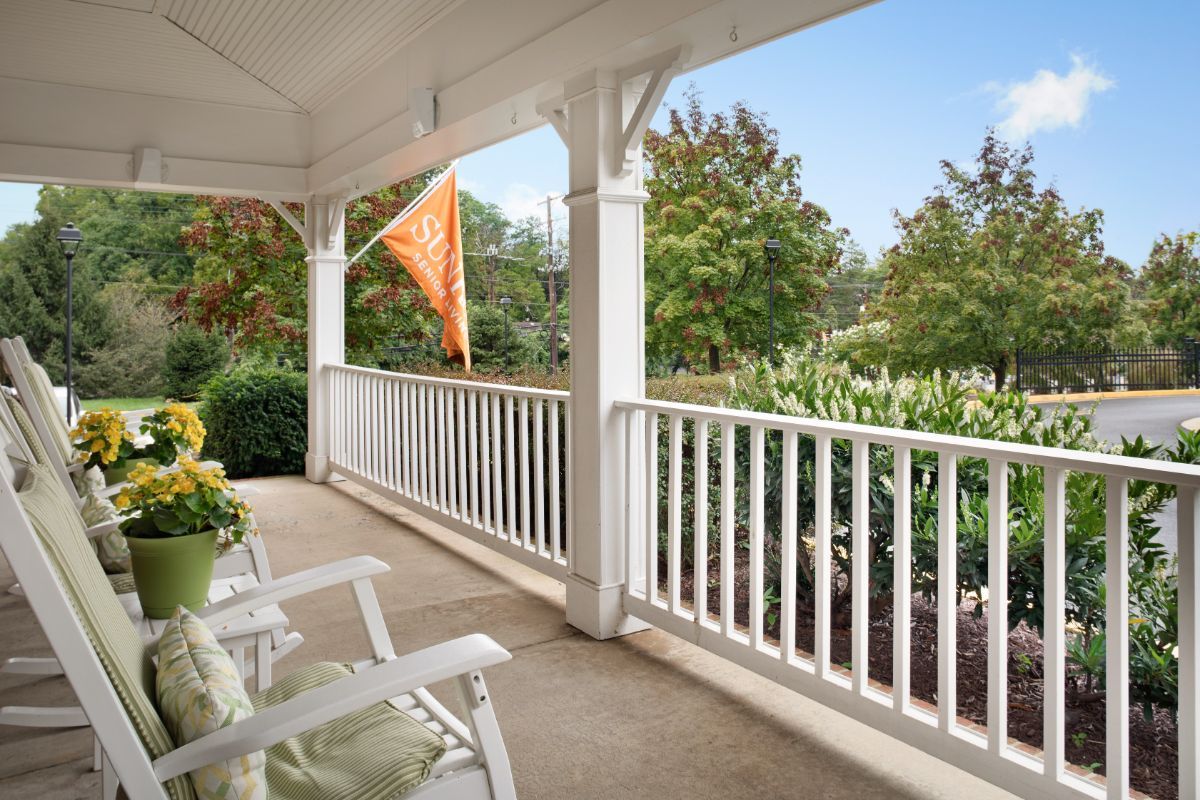 A cozy porch with rocking chairs overlooking a garden and trees.