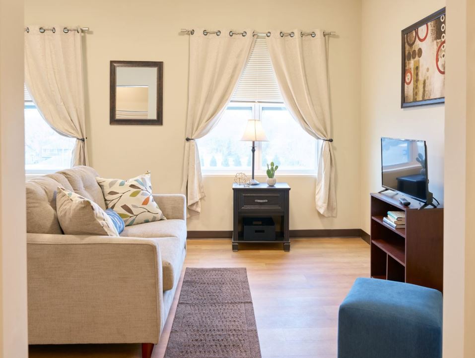 A cozy living room with a sofa, cushions, a television, and elegant curtains.