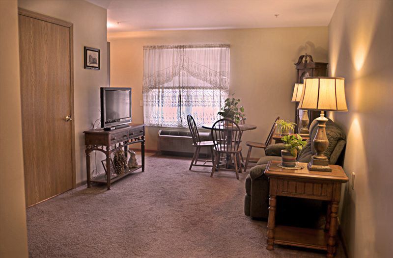 A cozy living room with comfortable seating and a television, featuring warm lighting and elegant decor.
