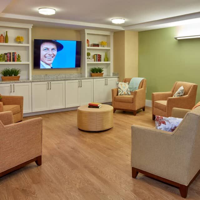 A cozy living room with comfortable armchairs and a television on the wall.