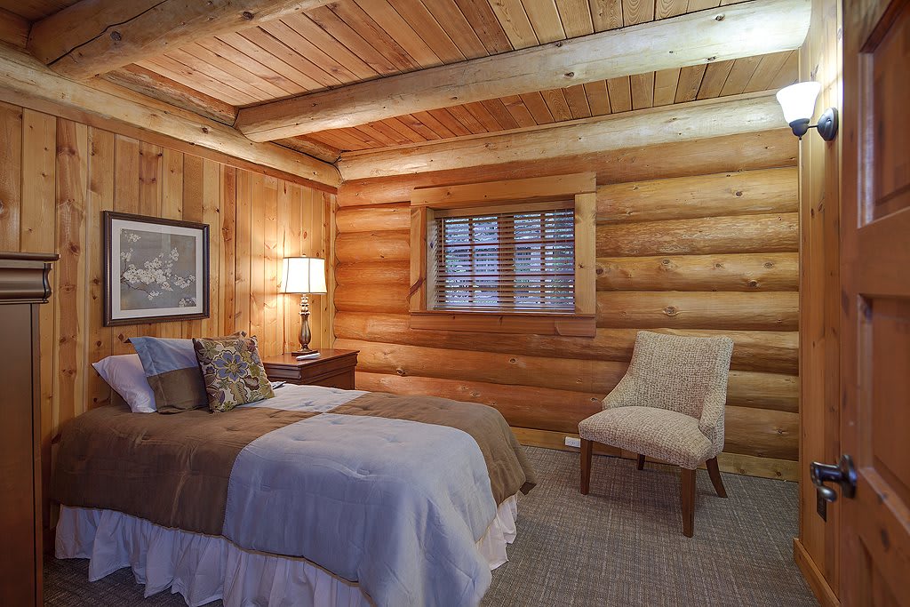 A cozy log cabin bedroom with a rustic wooden interior and comfortable furnishings.