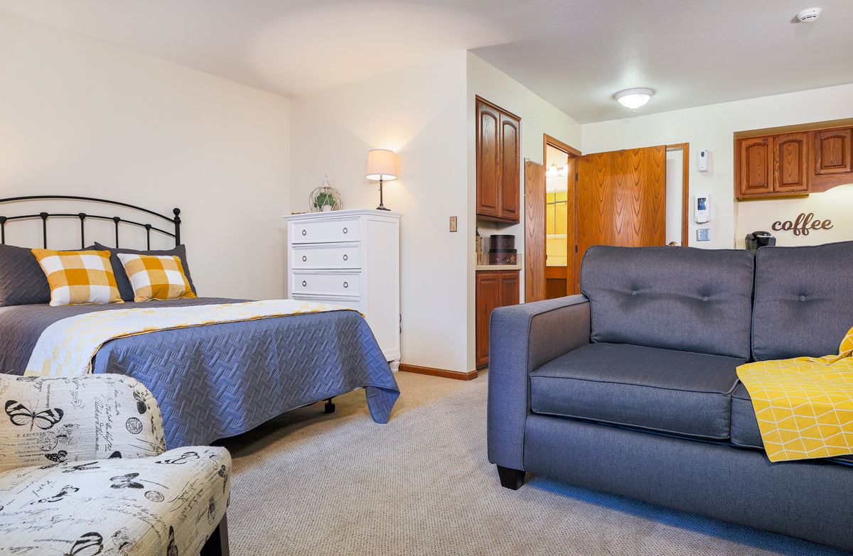 A cozy bedroom with a bed, armchair, and dresser.