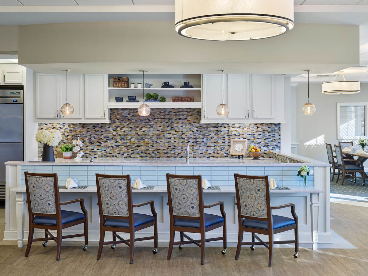 A modern kitchen interior featuring a mosaic backsplash, pendant lights, and seating at a spacious countertop.