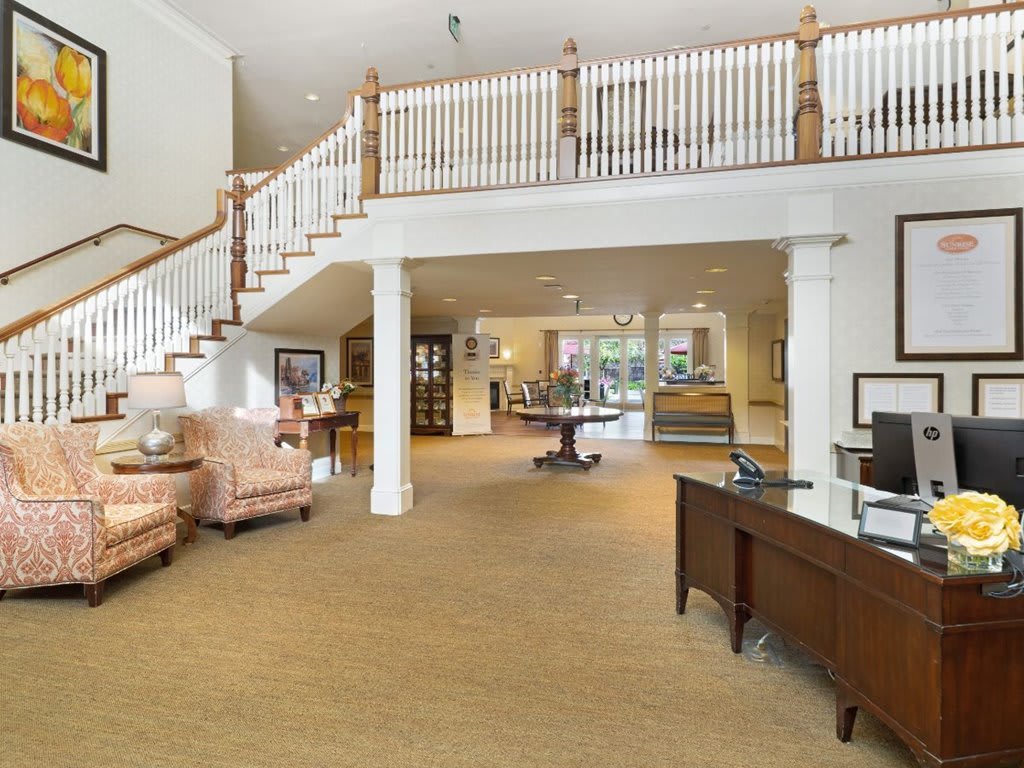 A spacious lobby area featuring a staircase, office desk, and comfortable seating.