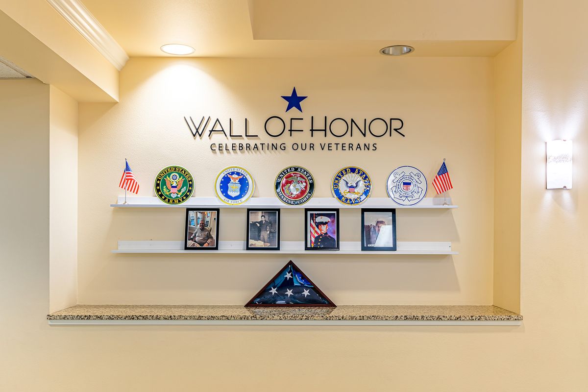 A Wall of Honor dedicated to veterans, featuring military emblems, photographs, and flags.
