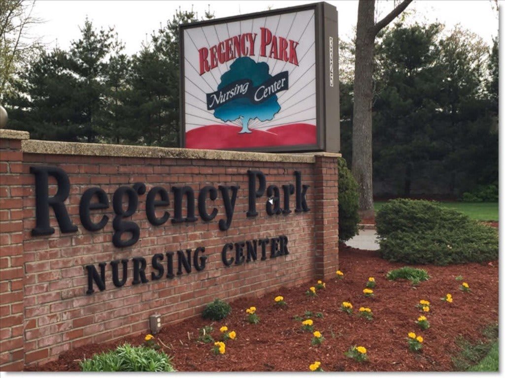 A sign for Regency Park Nursing Center surrounded by landscaped flowers and trees.