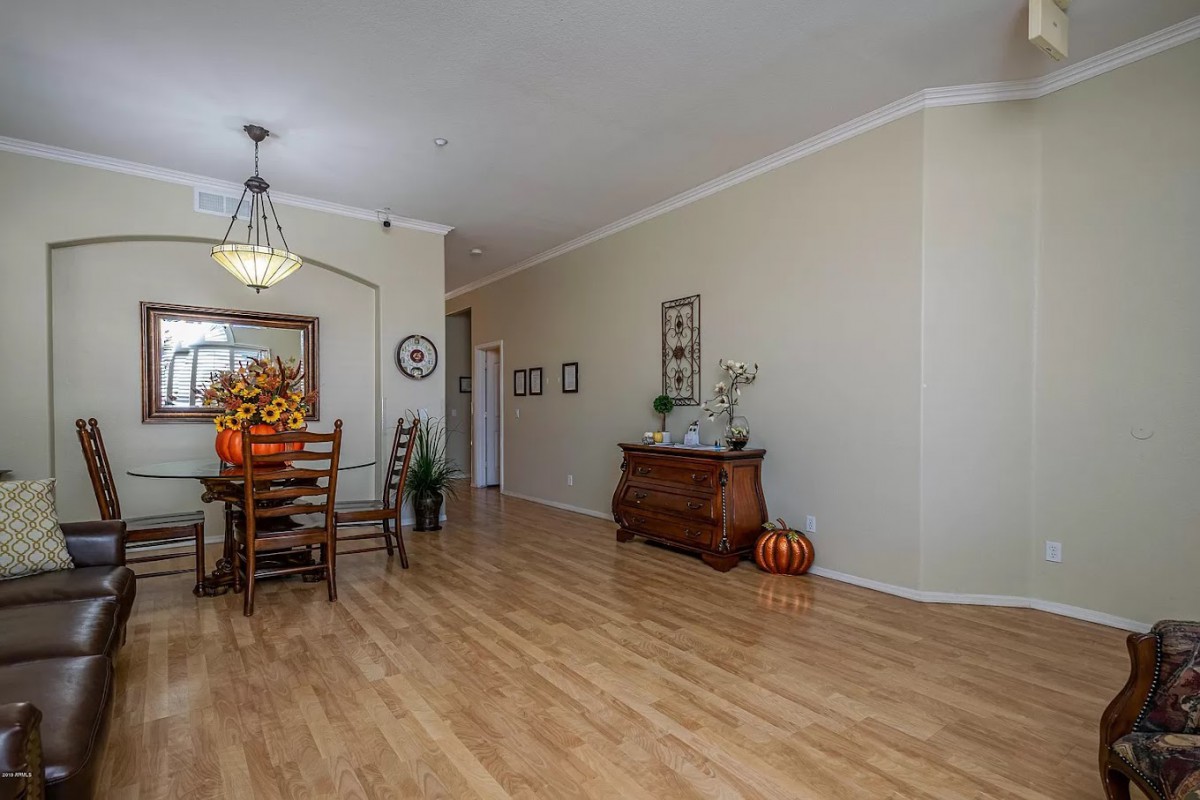 A spacious dining room with wood flooring, featuring a decorated table and elegant chandelier.