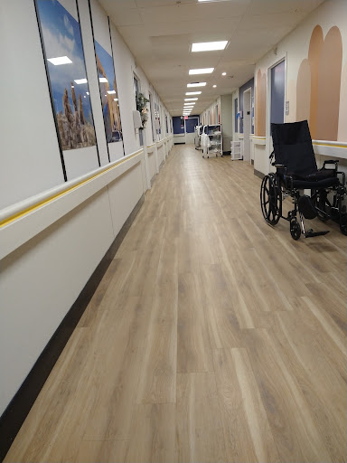 A quiet corridor in a healthcare facility, featuring a wheelchair and well-lit surroundings.