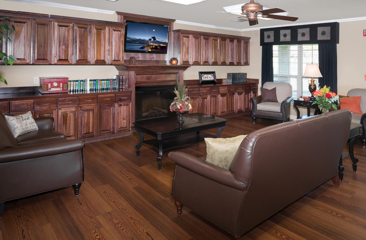 A cozy living room featuring wooden cabinets, a fireplace, and comfortable seating with a television above the mantel.