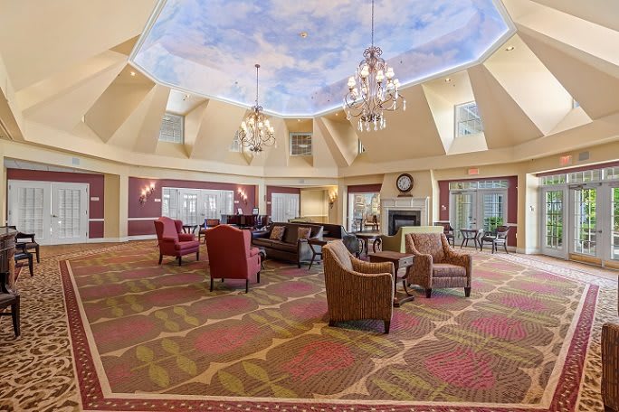A luxurious lounge with comfortable seating, chandeliers, and a skylight ceiling.