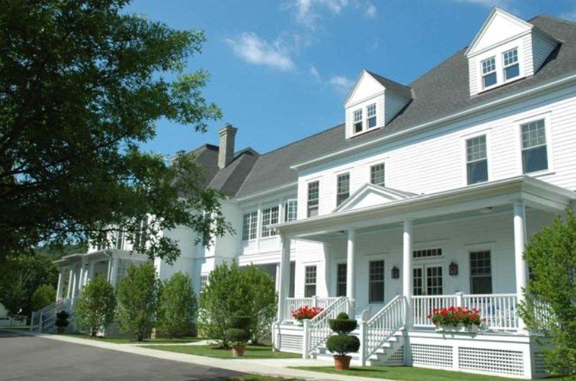 A white residential building with a porch and landscaping.