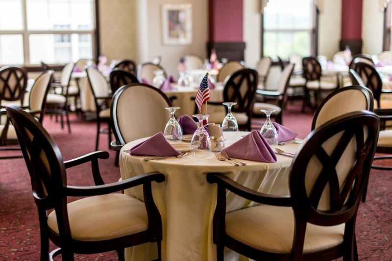 An elegant restaurant dining room with tables set for guests, featuring fine glassware and neatly folded napkins.