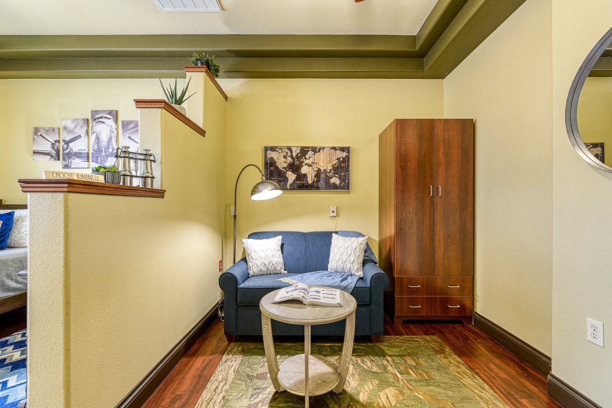 A cozy living room corner with a blue sofa, a standing lamp, and a small round table.