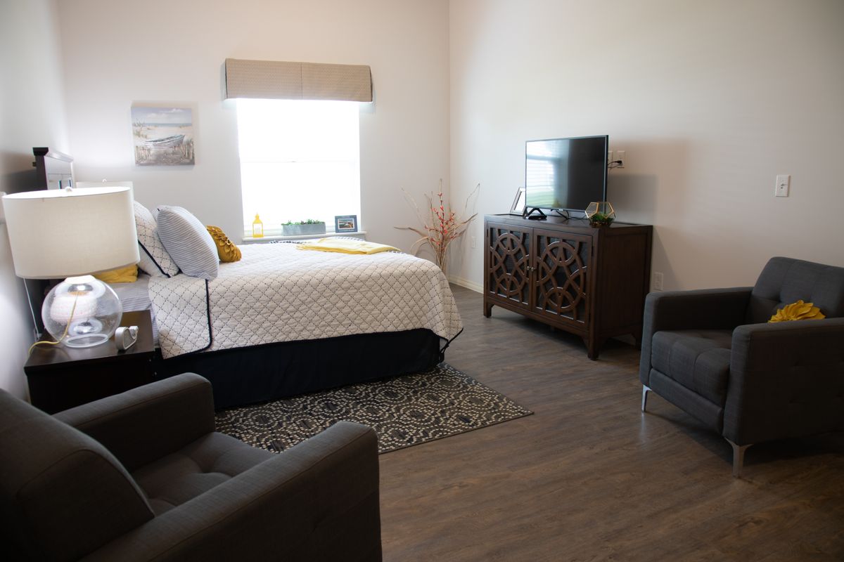 A modern bedroom with a neatly made bed, stylish furniture, and a flat-screen TV on a wooden cabinet.