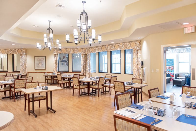 A bright and inviting dining room with multiple tables, chairs, and elegant chandeliers.