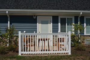 A small porch with white railings and patio furniture in front of a house.